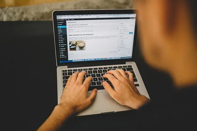 Notebook aberto com homem criando um site no WordPress